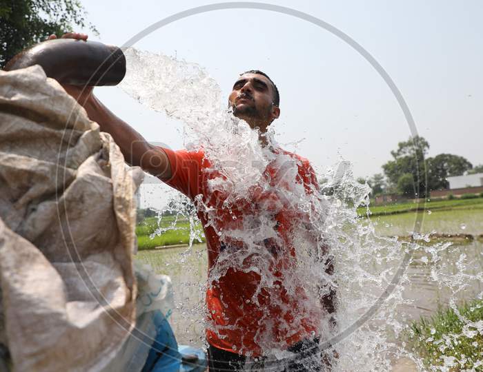 A young man enjoys the cool splash from a tube well on a hot summer day during Unlock 2.0 in Jammu on July 03, 2020.