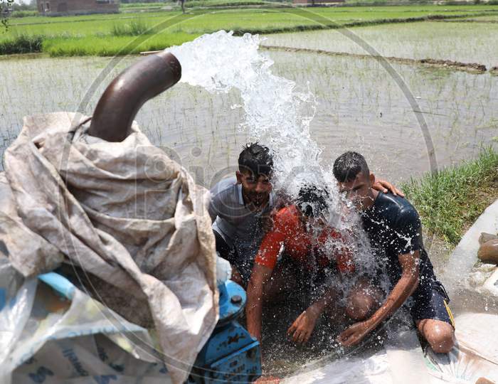 Three young men enjoy the cool splash from a tube well on a hot summer day during Unlock 2.0 in Jammu on July 03, 2020.
