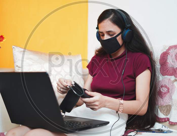 A Young Indian Girl Taking Out Cards From Her Wallet While Wearing A Mask On Her Face For Protection From Covid-19, Work From Home Concept.