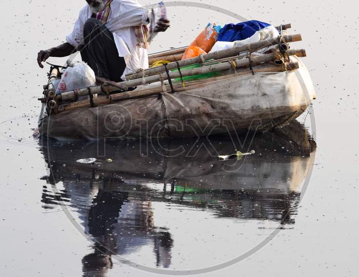 New Delhi, India - March 04, 2020: A man paddling a boat during morning time at Yamuna river ghat in New Deli, India