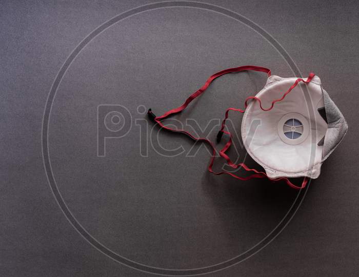 Face mask for protection against Covid 19 kept upside down on grey background showing respirator valve