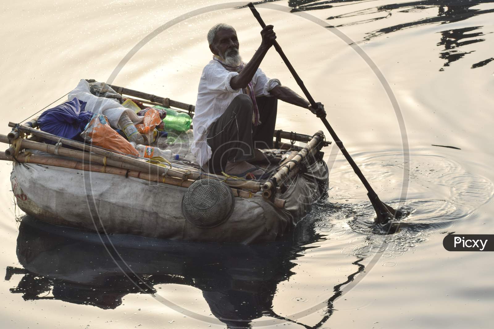 New Delhi, India - March 04, 2020: A man paddling a boat during morning time at Yamuna river ghat in New Deli, India