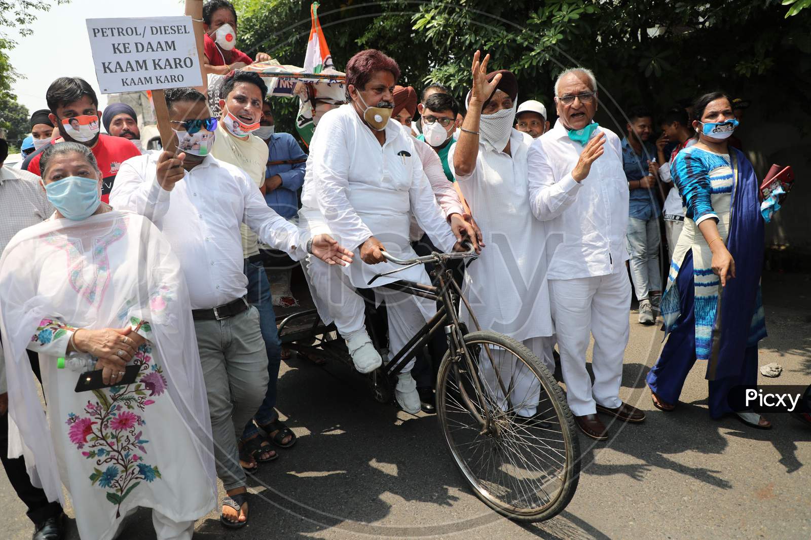 Senior Congress leader and former minister Raman Bhalla along with his party workers ride a bicycle rickshaw to protest the hike in the prices of petrol and diesel in Jammu on July 03, 2020.