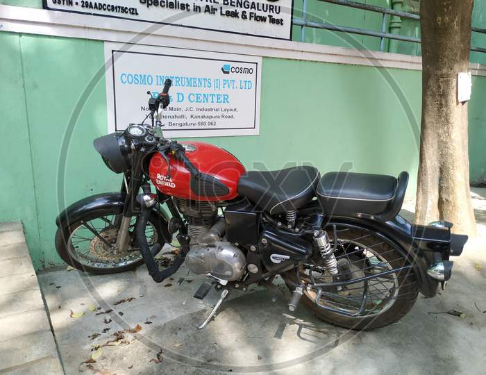 Closeup of Maroon or Red Color Royal Enfield bike Parking near Building Office Compound