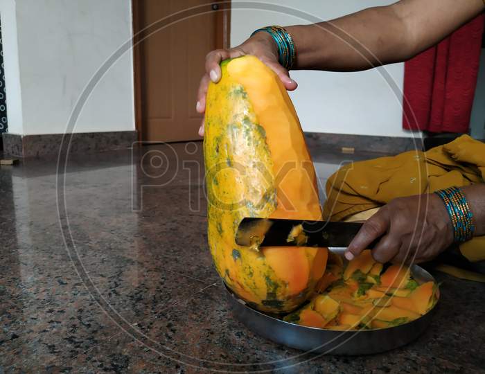 Indian Lady Removing Outer Skin of the Pappaya Fruit Using Knife