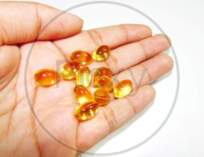 Hand holding Cod liver oil  or fish oil gel capsules  on white background. It contains omega 3 fatty acids , EPA,  DHA