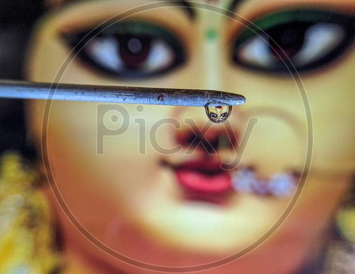 Maa Durga in waterdroplets under a stick, macro, closeup