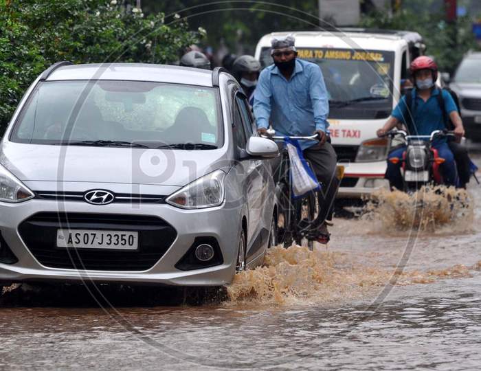 Commuters Wade Through A Waterlogged Street After Heavy Rainfall  In Guwahati On July 30, 2020.