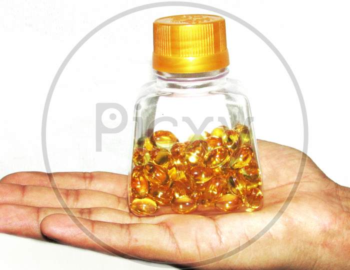 Hand holding Cod liver oil  or fish oil gel capsules  on white background.