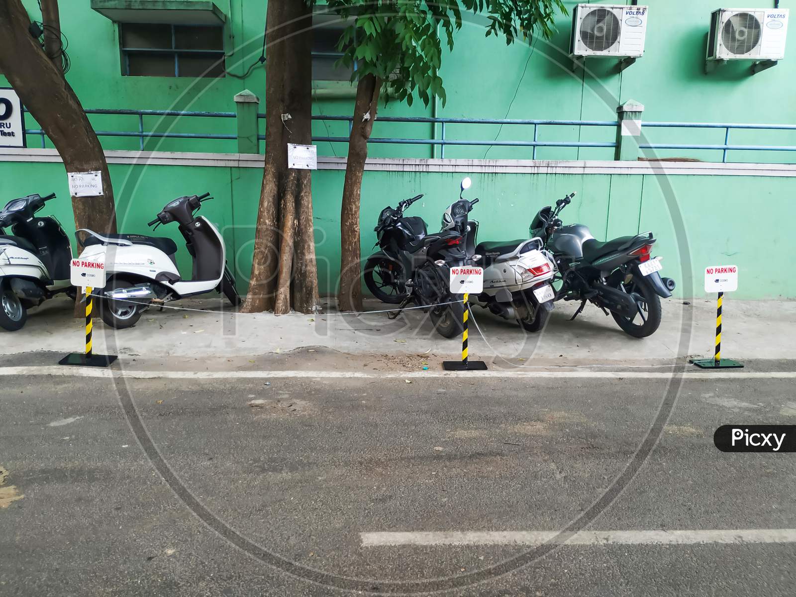 Closeup of Two Wheeler or Bikes Parking near the compound of the building with no parking metal stand for other than companies.