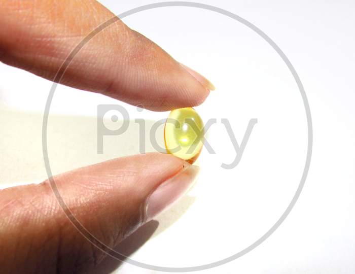 Hand holding Cod liver oil  or fish oil gel capsules  on white background. It contains omega 3 fatty acids , EPA,  DHA