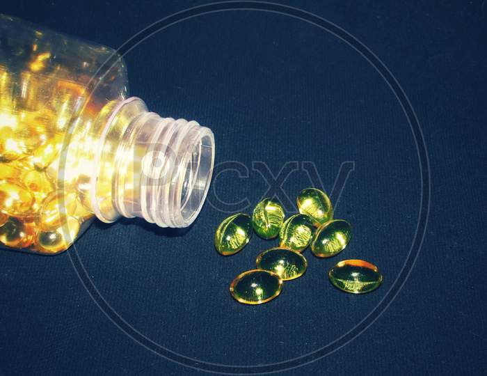 Cod liver oil  or fish oil gel capsules in jar and outside on black  background.