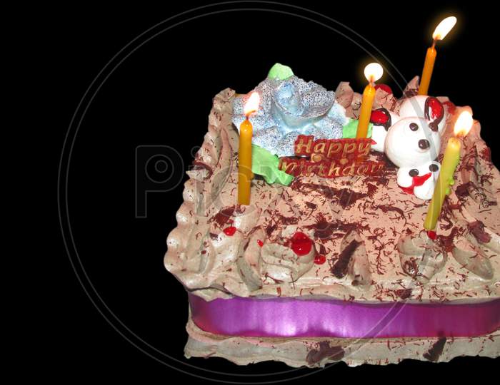Birthday Drip Cake And Burning Candles With Chocolate And Sprinkles Isolated Black Background Banner With Party Decor. Celebration Concept. Trendy Drip Cake