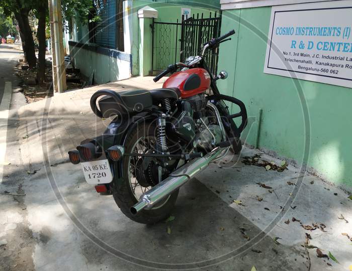 Closeup of Maroon or Red Color Royal Enfield bike Parking near Building Office Compound