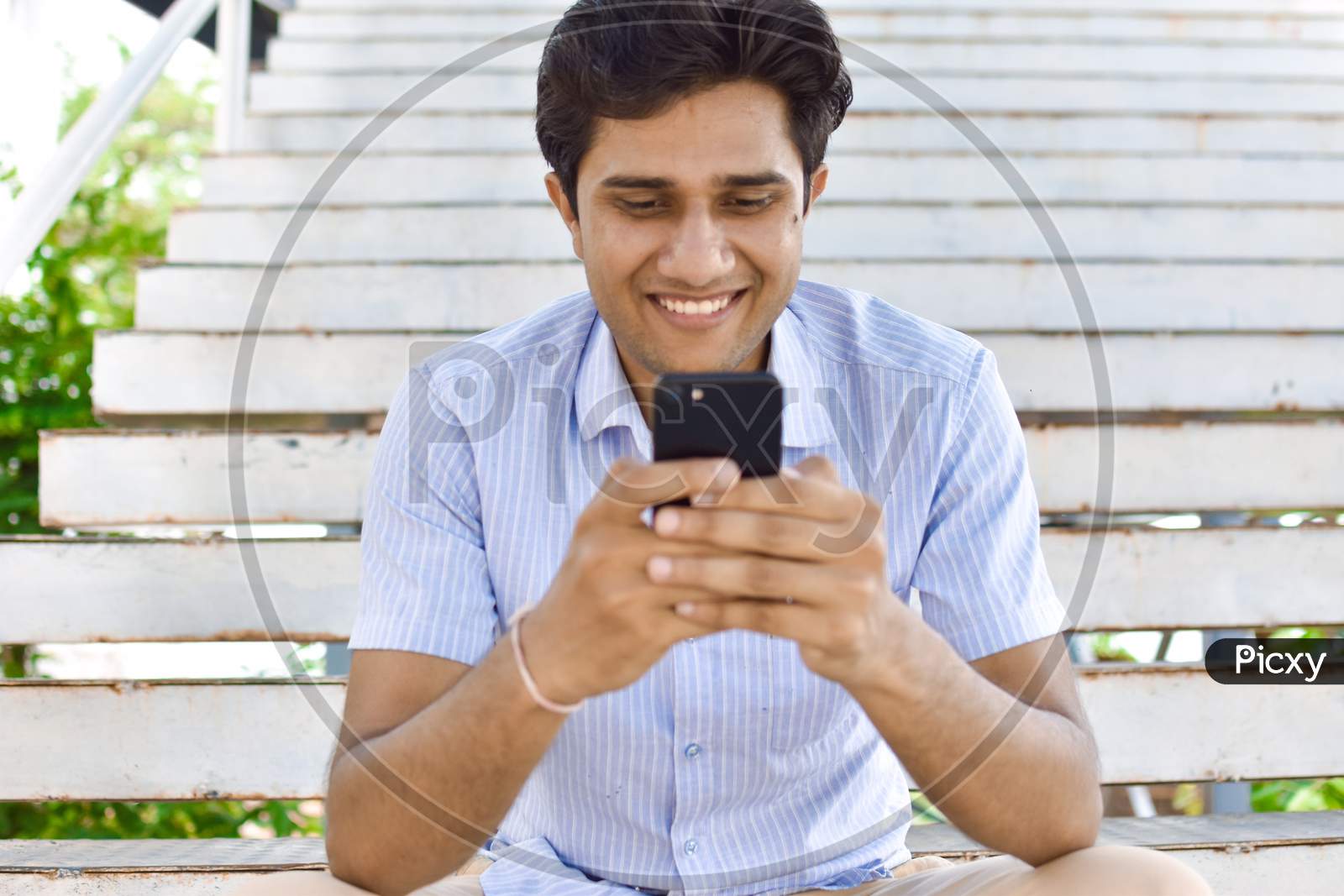 indian college student playing mobile phone