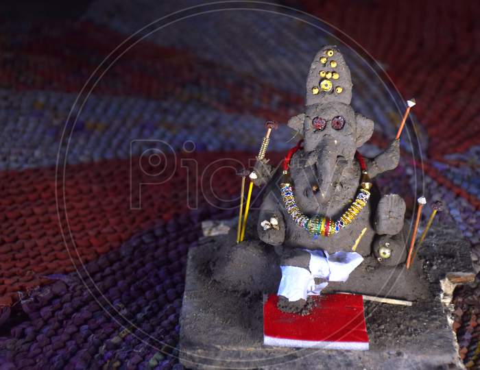 Lord Ganesha In Selective Focus, Made Of Clay With Colorful Blur Background, In Indian Village