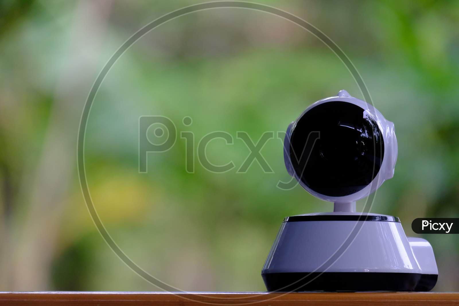 A White Modern Indoor Cctv Camera With Internal Infrared Is Rotating To Check Home Security With Wireless Connection Via Smartphone'S Application By Internet Ip Controlled With Blurred Background