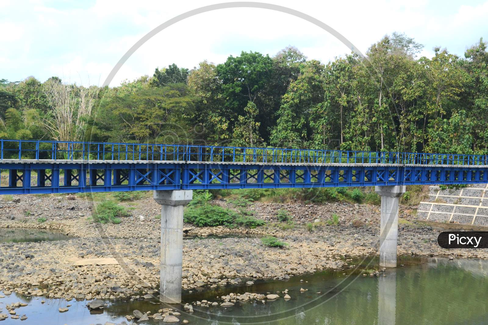 Long Blue Iron Bridge With Two Pillars On The River
