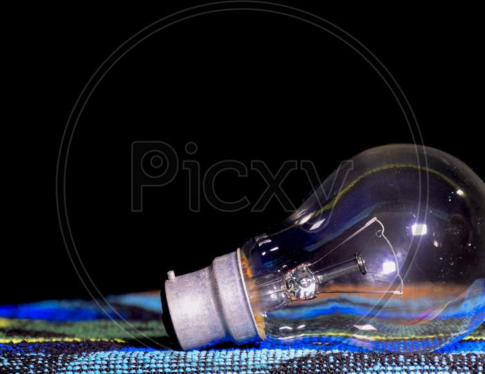 Old Incandescent Lamp In Black Background On Green Cloth.