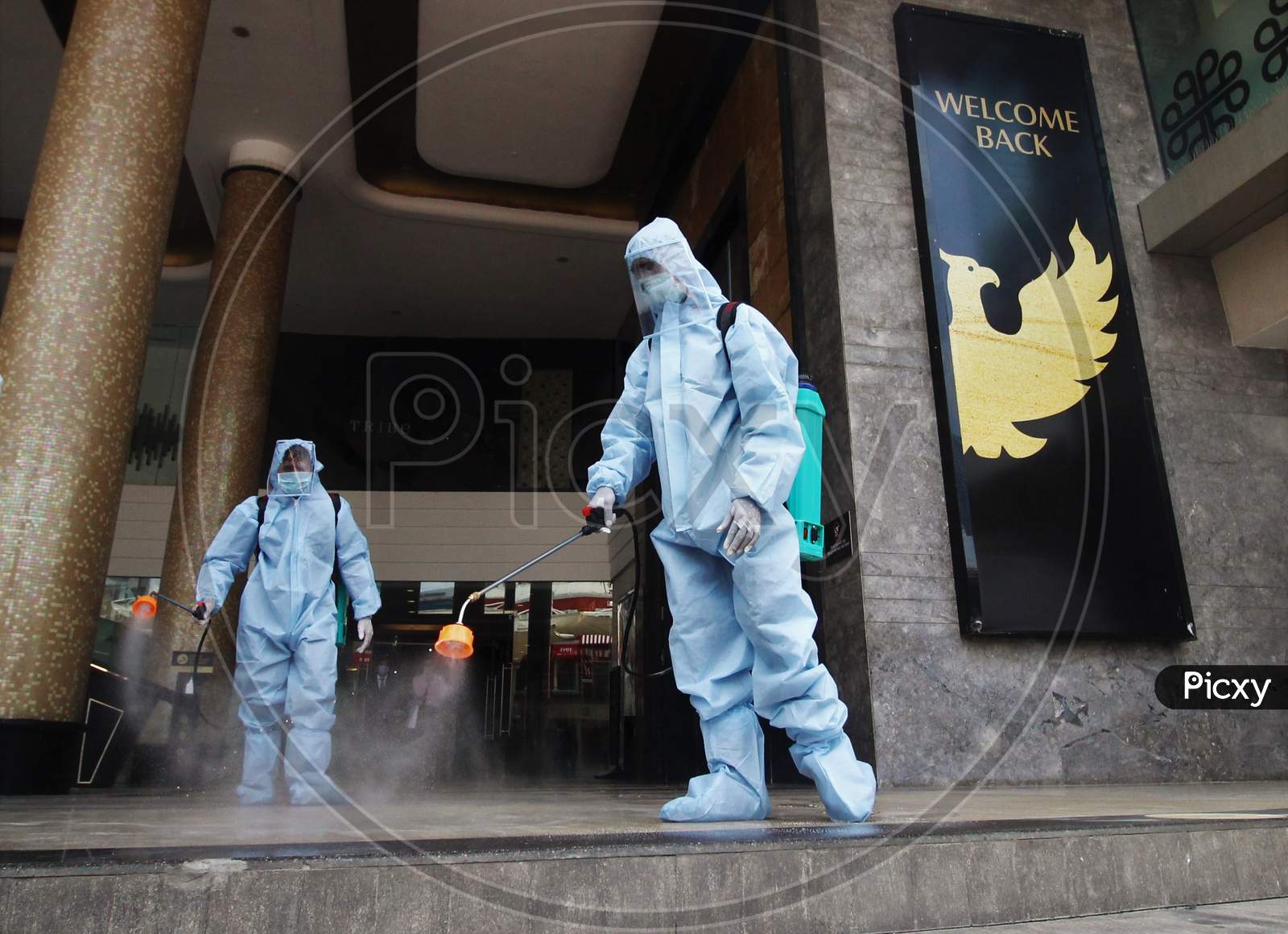 A man in personal protective equipment (PPE) sprays disinfectant to sanitize a mall before they reopen in Mumbai, India on July 30, 2020.