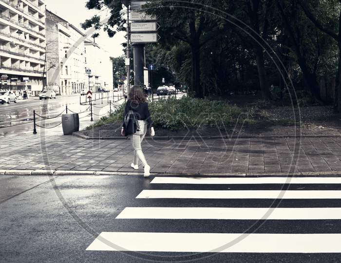 Krakow, Poland - July 18, 2020: A Wide Angle Shot Of Zebra Patterns On A Street Of Europe And A Female Crossing The Road