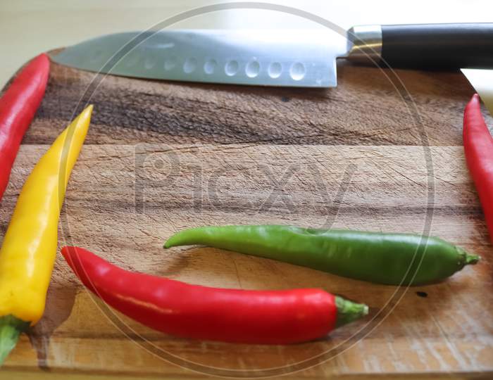 Top And Perspective View Of Chili Pepper And Steel Knife On A Wooden Cutting Board With An Isolated Background