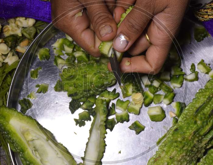 A Woman,S Hand And Pieces Of Bitter Gourd Cutting Bitter Gourd With A Knife
