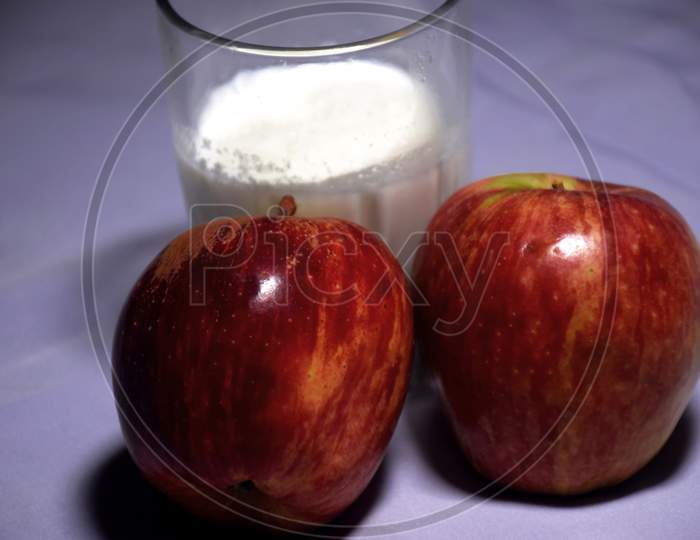 Glass Of Milk And Red Apples On White Cloth Background