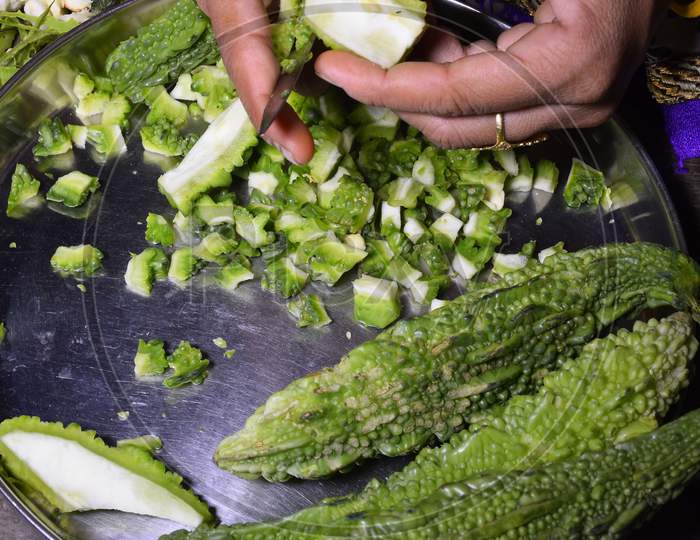 A Woman,S Hand And Pieces Of Bitter Gourd Cutting Bitter Gourd With A Knife