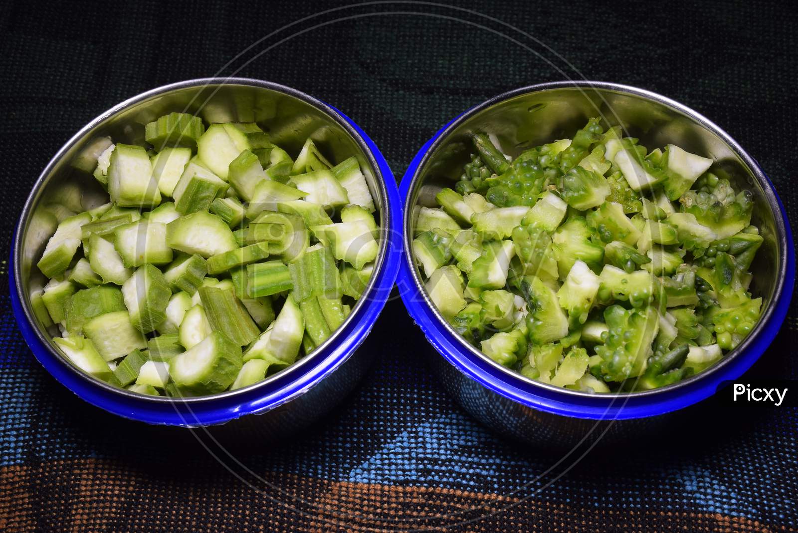 Fresh Bitter Gourd And Okra Fruits Pieces In Two Bowls,
