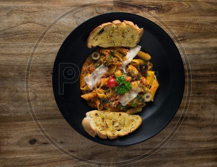 Penne pasta in tomato sauce with chicken, tomatoes decorated with parsley on a wooden table, Penne pasta with meatballs in tomato sauce and vegetables in bowl. Top view. Flat lay
