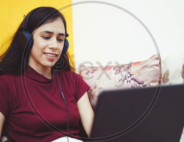 Close Up Of A Young Indian Girl Working On Her Laptop Wearing Headphones, Work From Home Concept.
