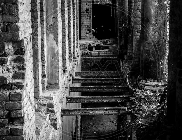 Old Abandoned Haunted House With Fragile Walls In Parallel And Sunlight Coming Through The Walls. Monochrome Shot