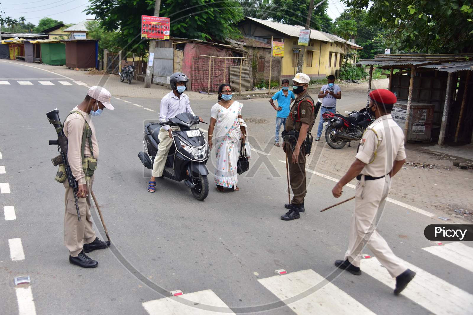 Security personnel question commuters who defied the curfew imposed during the lockdown by the Assam government to control the spread of the coronavirus in Nagaon, Assam on July 04, 2020