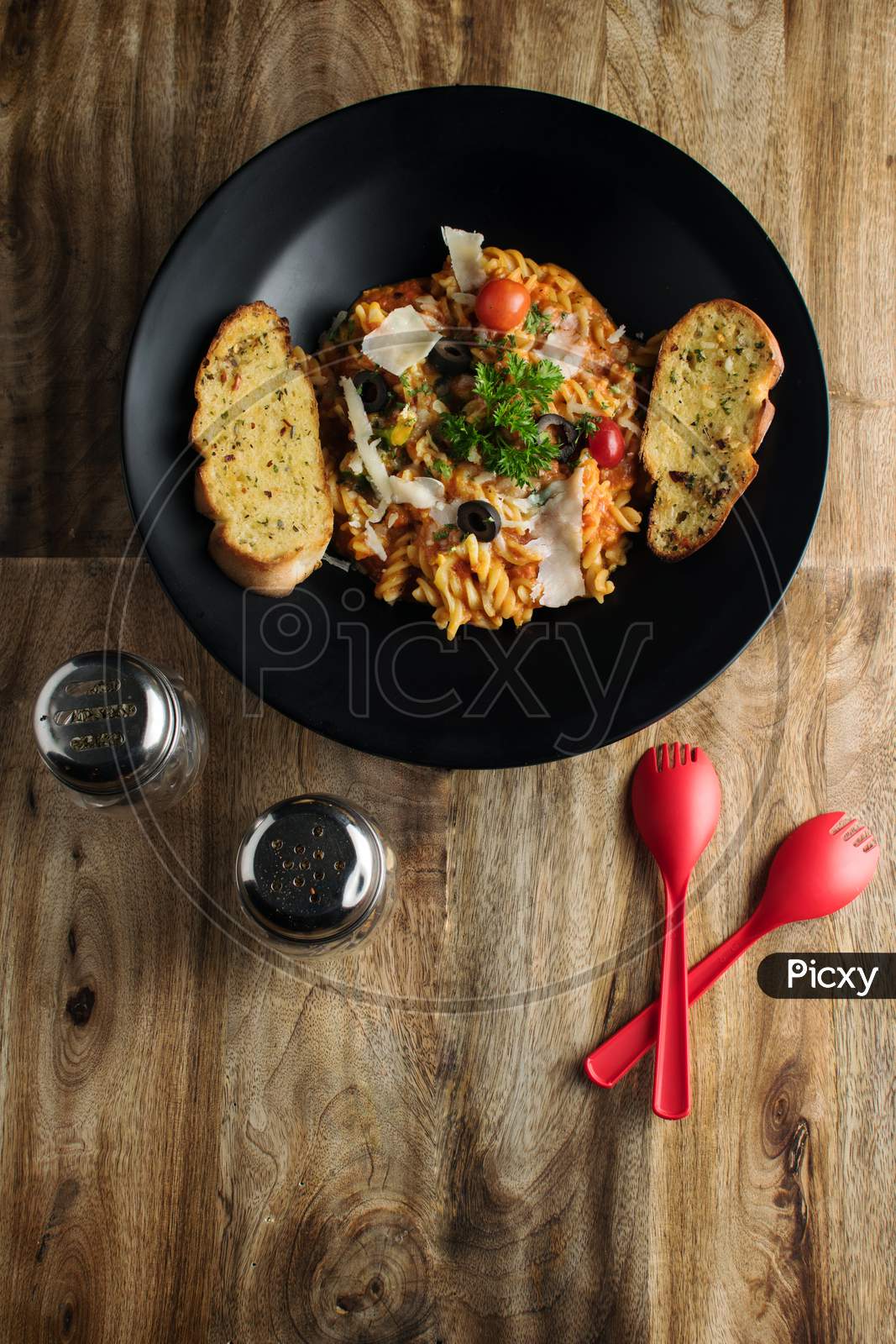 Penne pasta in tomato sauce with chicken, tomatoes decorated with parsley on a wooden table, Penne pasta with meatballs in tomato sauce and vegetables in bowl. Top view. Flat lay