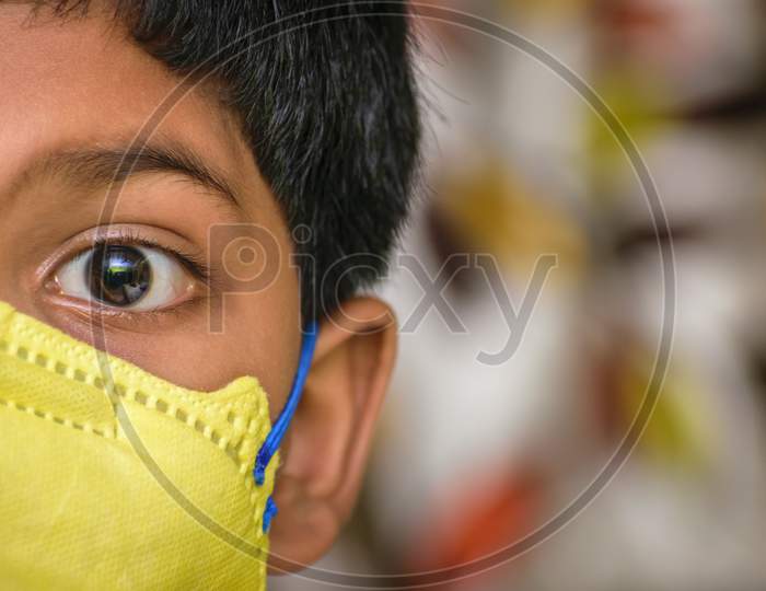 Isolated Young Indian Boy With Prominent Eyes Wearing N95 Face Mask For Protection Against Covid 19. Space For Text In Right