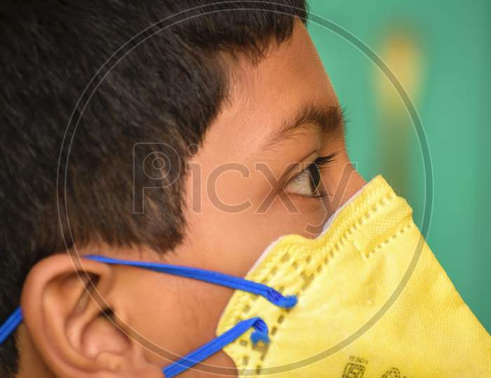 Isolated Young Indian Boy With Prominent Eyes Wearing N95 Face Mask For Protection Against Covid 19. Side View