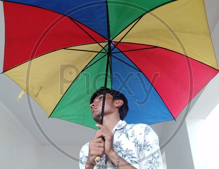 The boy stands with the umbrella