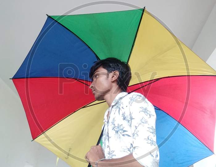 The boy stands with the umbrella
