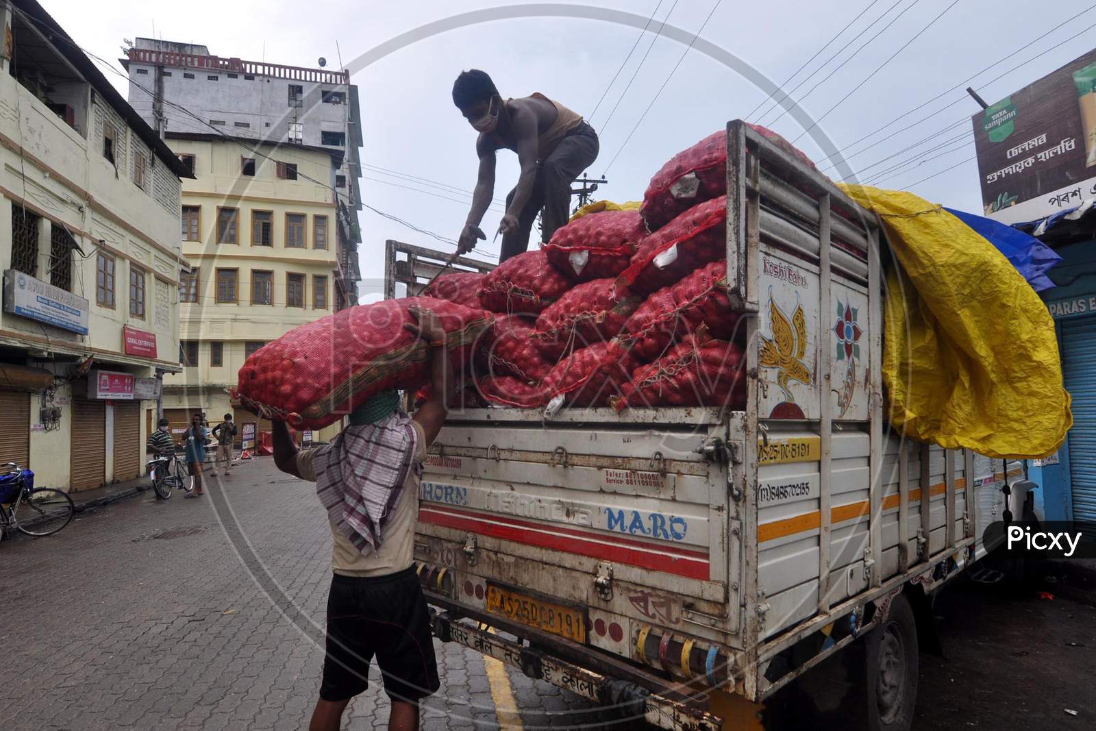 Two labourers unload a sack of onions from a vehicle at a wholesale market after the Assam government eases the lockdown in Guwahati, Assam on July 05, 2020