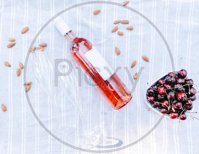 Rose Wine Bottle With Glasses And Cherry Picnic Background