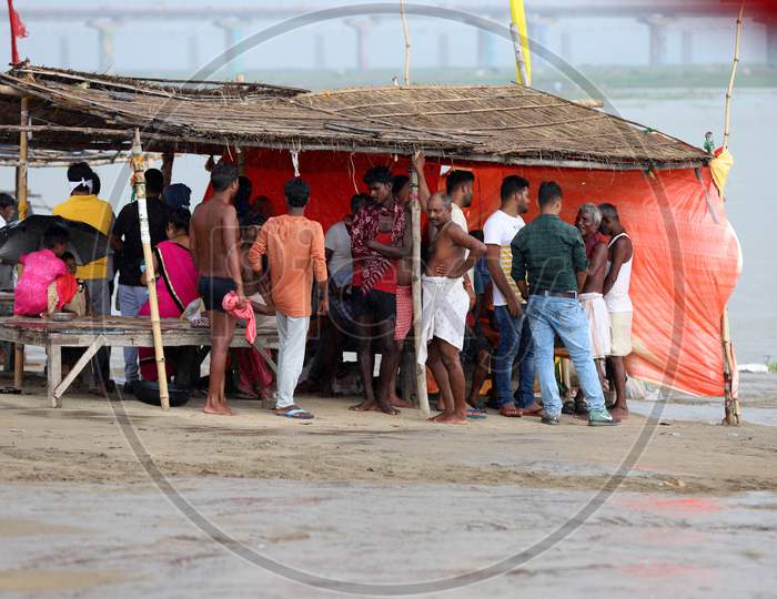 People take shelter under a hut on the banks of river Ganga during a heavy downpour in Prayagraj, Uttar Pradesh July 07, 2020