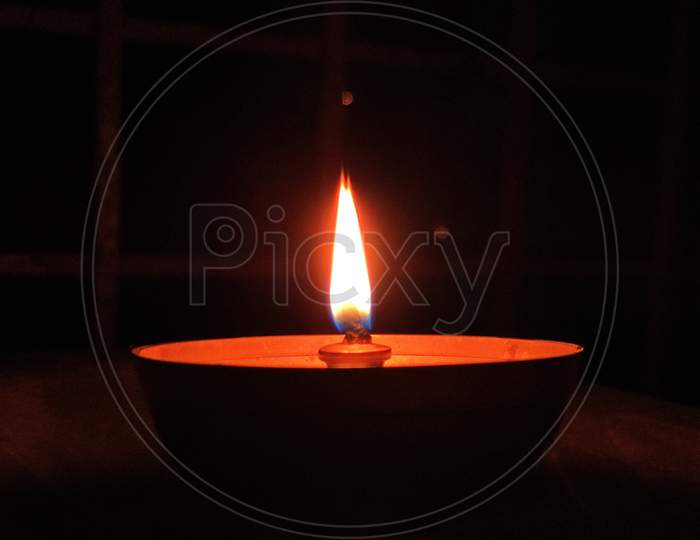 A Gold Color Diya with orange color light In A Balcony.