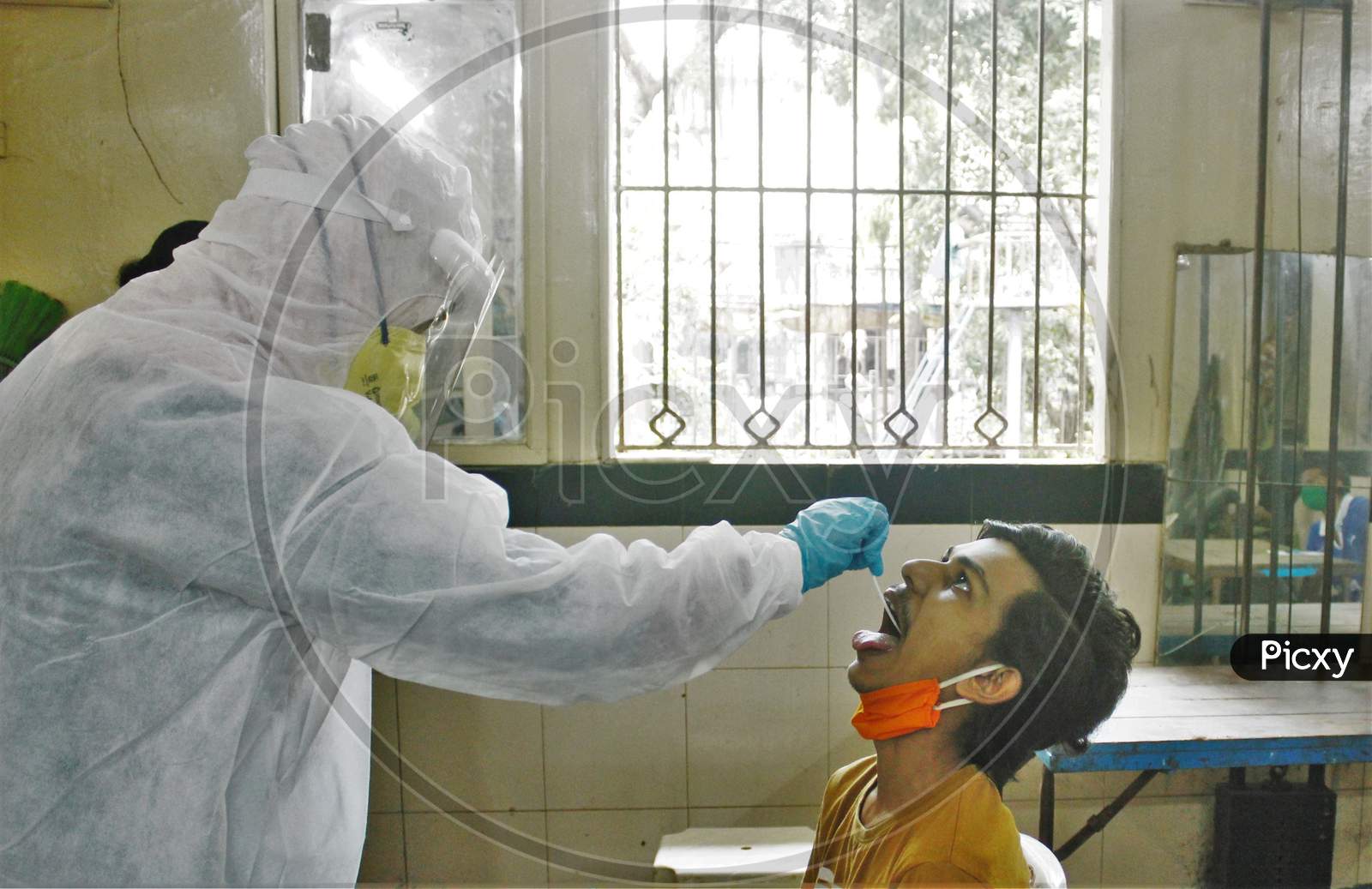A healthcare worker wearing personal protective equipment (PPE) collects a swab sample from a resident during a check-up campaign for the coronavirus disease (COVID-19), in Mumbai, India on July 1, 2020.