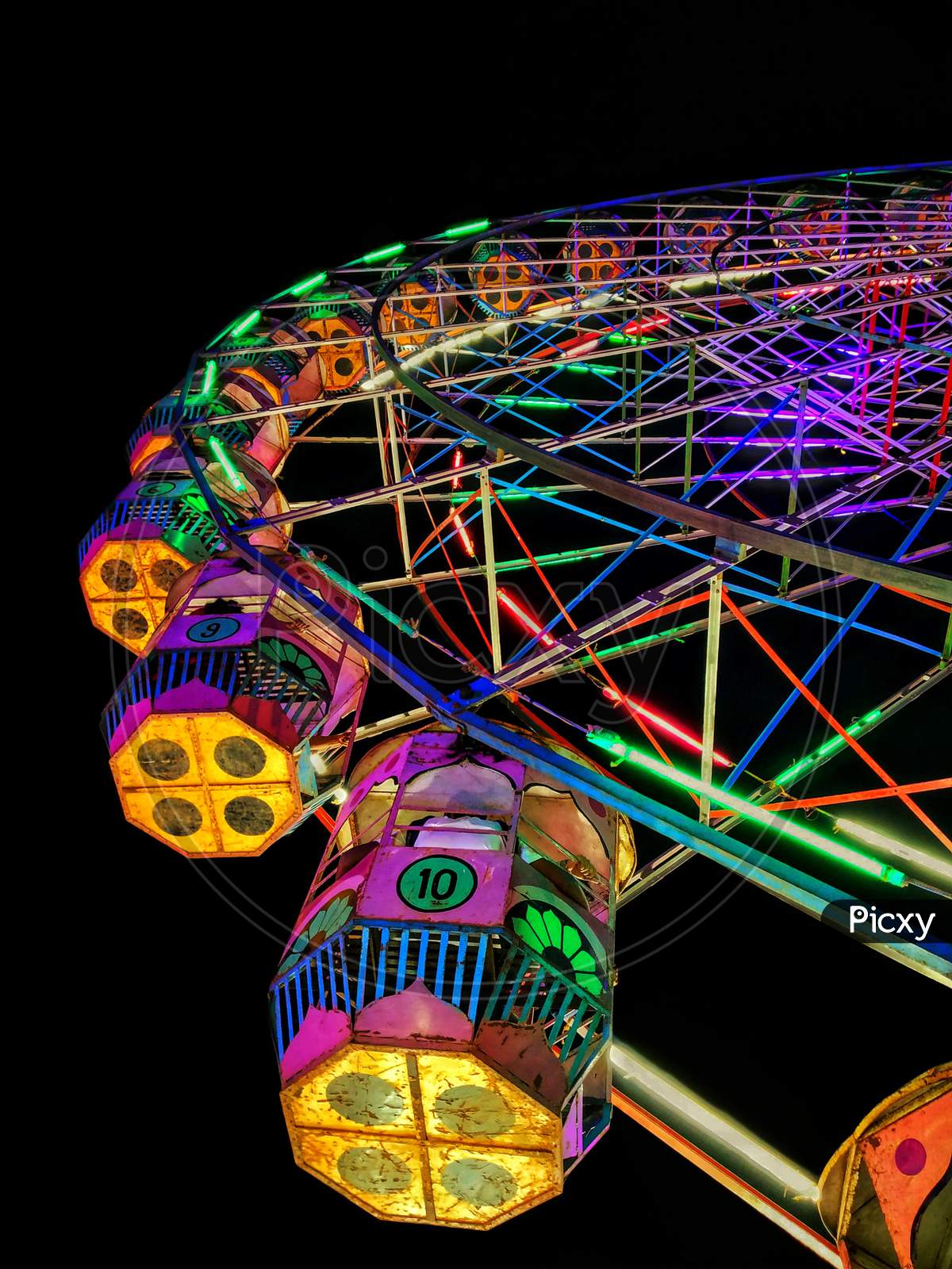 A Colourful Giant Wheel With Lights At A Fair Near A Beach.