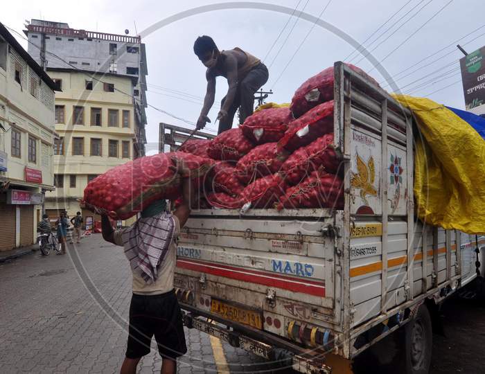 Two labourers unload a sack of onions from a vehicle at a wholesale market after the Assam government eases the lockdown in Guwahati, Assam on July 05, 2020