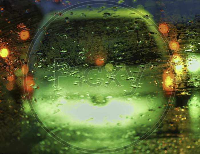 An Abstract Art Image Of Raindrops On A Glass Against Street Light