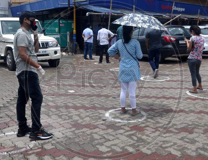People maintain social distance as they stand outside a grocery shop after the government eases lockdown in Guwahati, Assam on July 06, 2020.