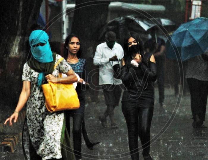 People walk on the road during heavy rains, in Mumbai on July 4, 2020.