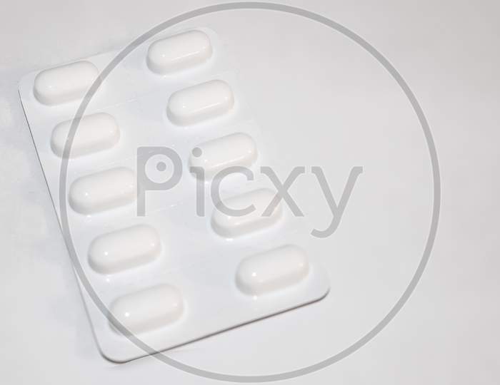 Pharmacy Drugstore Concept. Packs Of White Pills Packed In Blisters With Copy Space Isolated On A White Background. Focus On Foreground, Soft Bokeh.